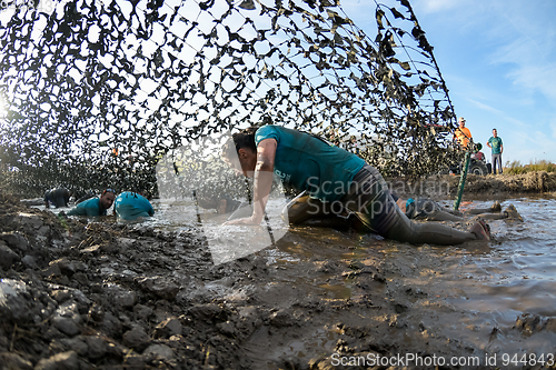 Image of Athletes crawling through mud