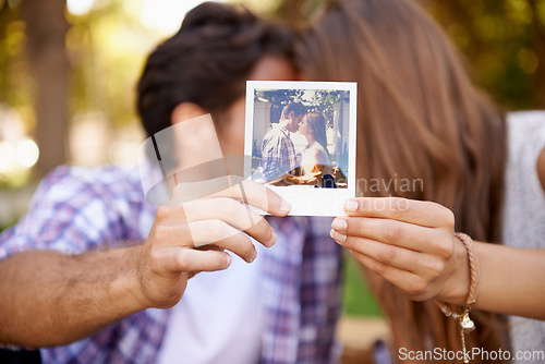 Image of Couple, photograph and valentines day date with love, kiss and affection in outdoor park for memory. Happy man and woman together on a picnic with polaroid paper picture in hands on holiday outdoor