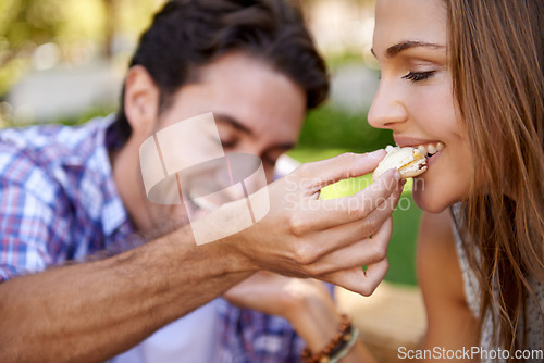 Image of Couple picnic, romantic and feeding on grass lawn with happiness, kindness and love on valentines date. Man, woman and eating together at nature park with food for bonding, romance and care by trees