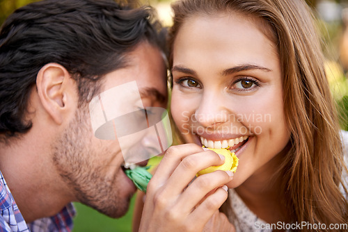 Image of Man, woman and picnic portrait with candy feeding on lawn with happiness, kindness or valentines day love. Happy couple, macaroon or together at nature park with sweets for bonding, romance or care