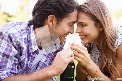Image of Nature, happy and couple sharing a drink with love on a summer picnic date in an outdoor garden. Happiness, smile and young man and woman drinking a bottle of cola together relaxing on grass in field