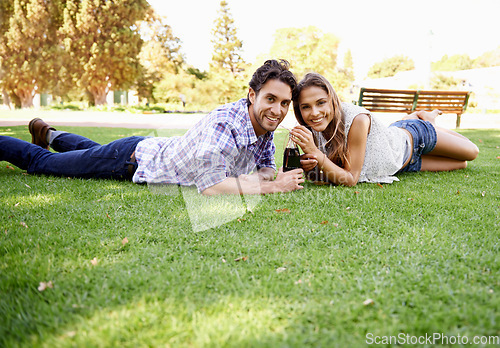 Image of Happy couple, park and valentines day date portrait with a drink on grass for love, bonding and time together. Smile of a young man and woman in nature for a summer picnic with a cola bottle outdoor