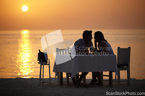 Image of Love, ocean sunset and couple at table for romantic valentines day date at the beach in Bali in silhouette. Romance, food and wine on vacation for man and woman in loving relationship in Indonesia