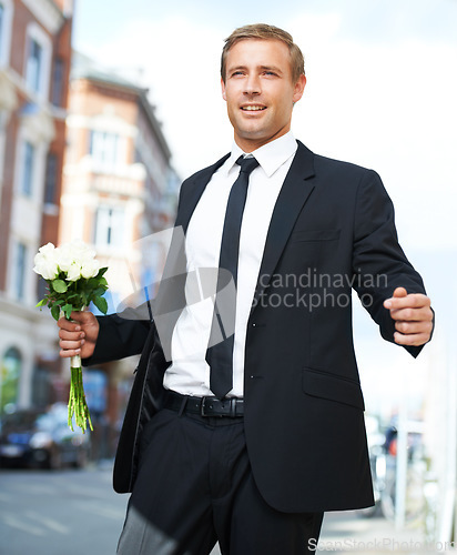 Image of Man, gift and valentines day flowers or roses on a city street for a date, love and motivation. Model person in a formal suit with a flower bouquet to celebrate holiday or event with urban travel