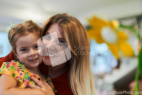 Image of A cute little girl kissing and hugs her mother in preschool