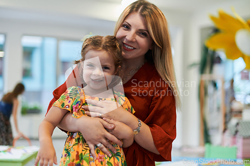 Image of A cute little girl kissing and hugs her mother in preschool