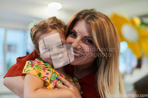 Image of A cute little girl kissing and hugs her mother in preschool