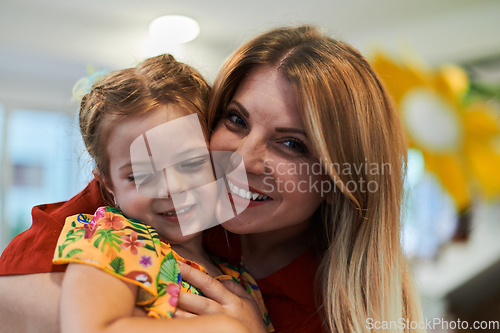 Image of A cute little girl kissing and hugs her mother in preschool