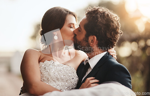 Image of Love, wedding and kiss with a couple outdoor on their marriage day together for romance or tradition. Event, celebration or married with a birde and groom kissing outside after their ceremony