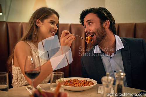 Image of Love, restaurant date and woman feeding man spaghetti on valentines day, happy and romantic dinner. Romance, valentine and food with wine, couple celebrate marriage or relationship with time together