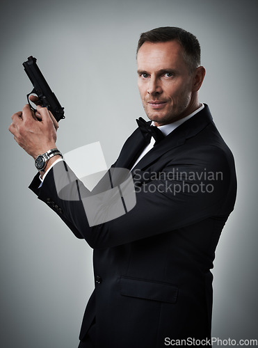 Image of Portrait, gun and man in studio with weapon for power, crime or secret mission on grey background. Face, handgun and mature guy model ready to shoot with mockup, assassin or hitman aesthetic isolated