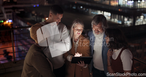 Image of Tablet, collaboration and night with a business team working together in the city on their office balcony. Finance, teamwork and meeting with a man and woman employee group talking strategy outside