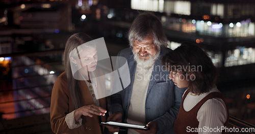 Image of Tablet, collaboration and night with a business team working together in the city on their office balcony. Finance, teamwork and meeting with a man and woman employee group talking strategy outside