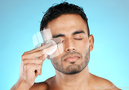 Image of Man, cotton and man in studio for skincare, wellness and cleaning while grooming on blue background. Faical, pad and male skin model relax with luxury, cosmetics and product, hygiene and isolated