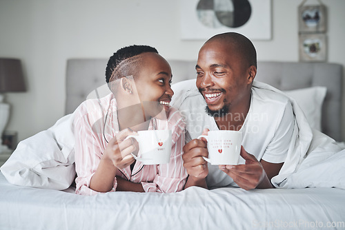 Image of Coffee, bed and morning with a black couple together in the bedroom of their home to relax on the weekend. Love, tea or early with young man and woman relaxing while bonding in their house