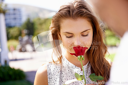 Image of Woman, smelling rose and outdoor for valentines day date at a city park with love, romance and beauty. Face of person with red flower as gift or present to celebrate Paris couple holiday in summer