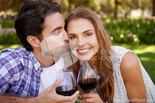 Image of Couple portrait, wine or cheek kiss on picnic date, valentines day or romance bonding in nature, park or garden. Smile, happy woman and man with alcohol drinks glass for love anniversary celebration