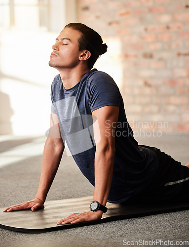 Image of Calm, yoga and man stretching in a gym with fitness, exercise and workout for wellness. Breathing work, pilates and body stretch of a athlete on the ground of a health and training center to relax