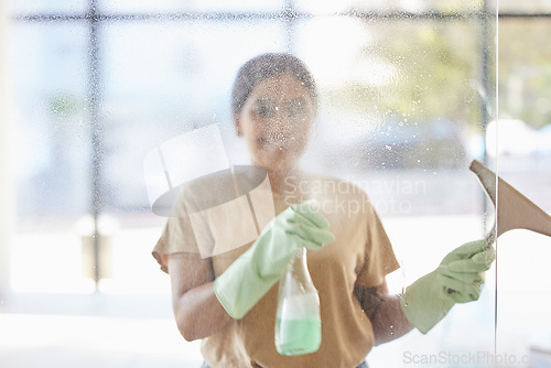 Image of Happy, woman and cleaning window with smile, spray bottle and soap or detergent housekeeping in home or hotel. Housework, smudge and housekeeper or cleaner service washing dirt off glass in apartment