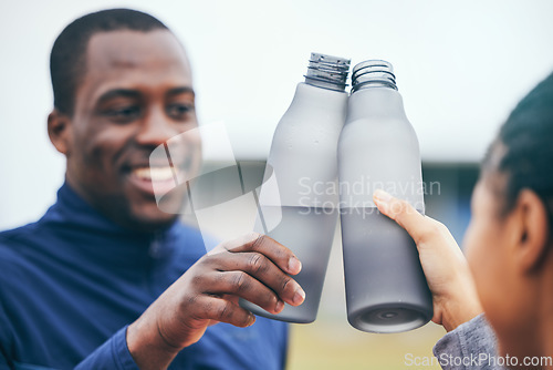 Image of Fitness, water bottle and black couple toast outdoors together after workout, exercise or training. Sports targets, celebration and man and woman cheers with liquid for hydration to celebrate goals.