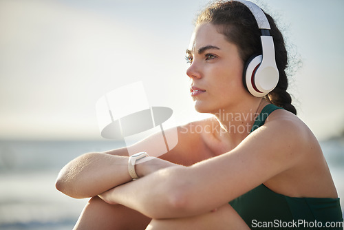 Image of Headphones, fitness and relax woman on beach for wellness, mental health and health in morning sky mockup. Thinking, ideas and calm sports person listening to music or peace podcast by ocean or sea