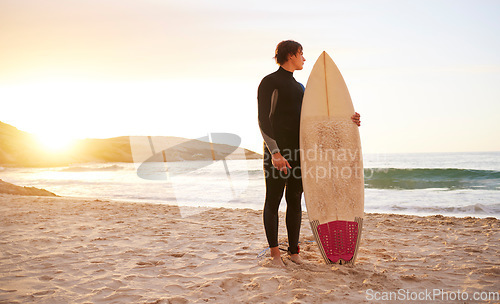 Image of Surfer, surf and man with surfboard at the beach, sea and ocean in sunset or the morning with mockup space. Young, ready and male in swimsuit on a sunny day on the sand, shore and water in summer