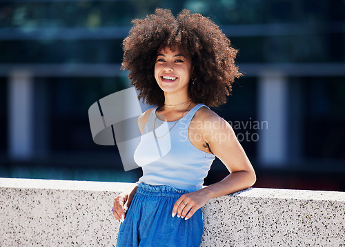 Image of Portrait, fashion and city with a black woman outdoor on a bridge, looking relaxed during a summer day. Street, style or urban and an attractive young female posing outside with an afro hairstyle