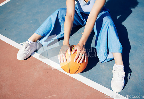 Image of Basketball, hands and woman on the outdoor court floor with urban fashion for influencer beauty. Sport, model and young person sitting with gen z clothes with sports game equipment in summer