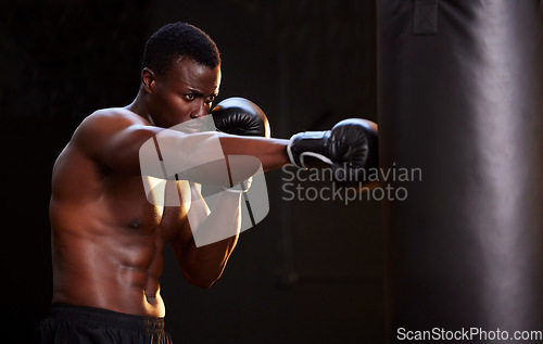 Image of Boxing, fitness and black man with training focus, energy and bodybuilder mindset in dark gym for workout. Challenge, boxer athlete or sports person with strong exercise in mma, martial arts and gear