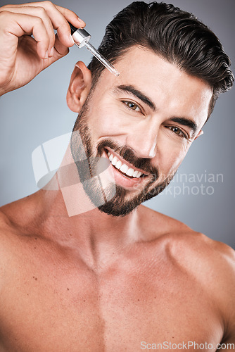 Image of Man, face and facial oil for skincare, beauty and cosmetic care, serum product in hand isolated on studio background. Portrait, smile and moisturizer, wellness and dermatology for healthy skin glow