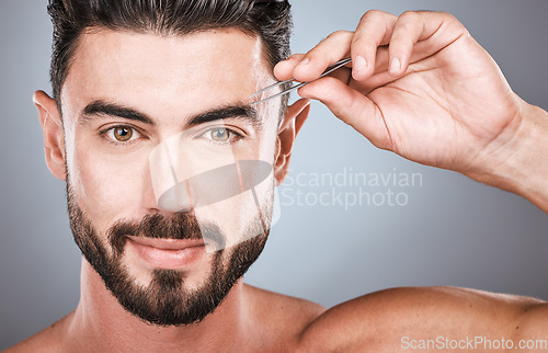 Image of Face portrait, eyebrow and man with tweezers in studio isolated on a gray background for wellness. Health, hair removal and male model with facial product to pluck eyebrows for grooming and beauty.