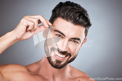 Image of Face, portrait and man with tweezers in studio isolated on a gray background for wellness. Health, hair removal and male model with product for plucking eyebrows for grooming, cleaning and hygiene.