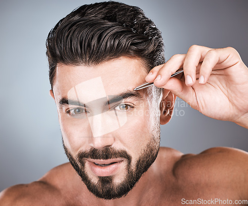 Image of Face, portrait and man with tweezers in studio isolated on a gray background for wellness. Health, hair removal and male model with facial product to pluck eyebrows for grooming, hygiene and beauty.