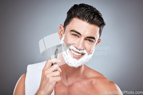 Image of Razor, face and man with shaving cream in studio isolated on a gray background. Beard, towel and portrait of happy male model with facial product, foam or gel to shave for wellness and hair removal.