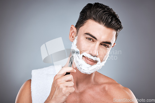 Image of Face, razor and man with shaving cream in studio isolated on a gray background. Beard care, towel and portrait of male model with facial product, foam or gel to shave for wellness and hair removal