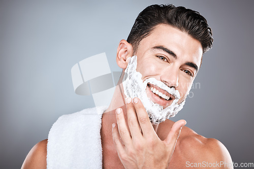 Image of Applying, shaving and portrait of a man with cream on face isolated on a grey studio background. Happy, hygiene and headshot of a person with a facial product for beard hair removal on a backdrop