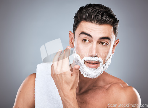 Image of Face, shaving foam and grooming with a man model in studio on a gray background for hair removal. Thinking, hand and skincare with a handsome young male in the bathroom for a shave in the morning