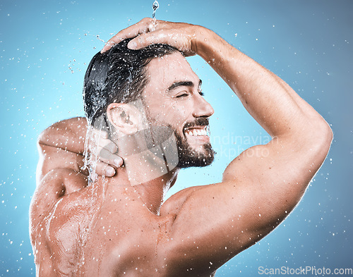 Image of Back skincare, water splash and man in shower in studio isolated on a blue background. Wellness, dermatology and face of happy male model cleaning, washing and bathing for healthy skin and hygiene.