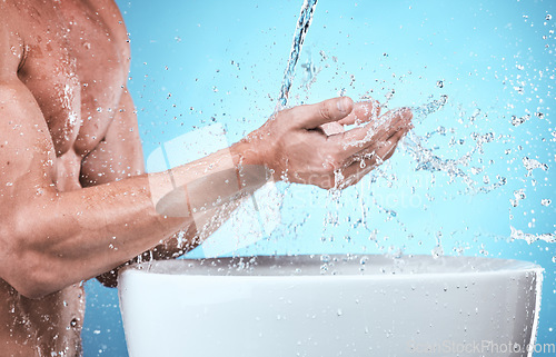 Image of Water splash, washing hands and cleaning man in studio isolated on a blue background for wellness, healthy skin or hydration. Skincare hygiene, dermatology and male model bathing to remove bacteria.