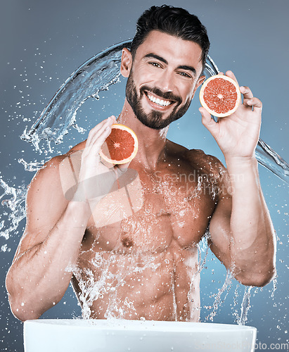 Image of Portrait, water splash and man with grapefruit in studio isolated on a blue background. Skincare, vegan fruits and happy male model washing or cleaning food for hygiene, healthy diet and vitamin c.