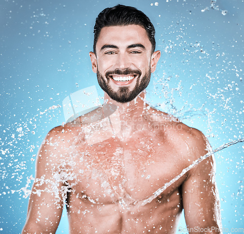 Image of Water drops, hygiene and shower with man in portrait for beauty and skincare isolated on blue background. Smile, face and cleaning body with muscle, sustainability and happy with natural cosmetics