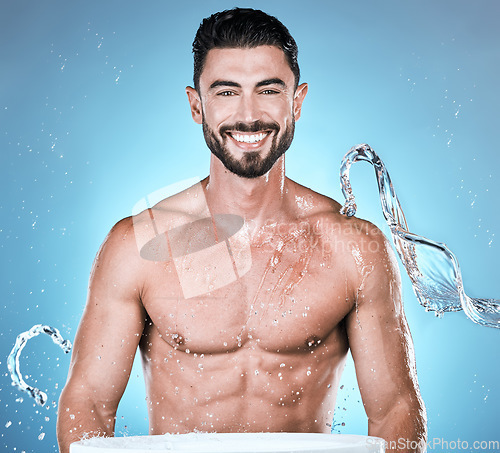 Image of Water splash, hygiene and shower with man in portrait for beauty and skincare isolated on blue background. Smile, face and cleaning body with muscle, sustainability and happy with natural cosmetics