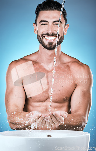 Image of Portrait, water splash and man cleaning hands in studio isolated on a blue background for wellness, healthy skin or grooming. Hygiene dermatology, skincare and male model bathing or washing hand.