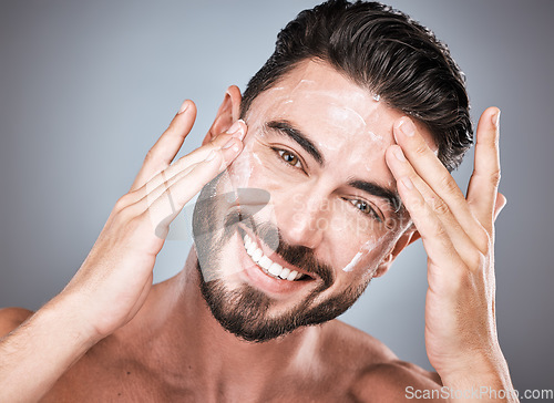 Image of Skincare, face and man with cream in studio isolated on a gray background for facial wellness. Portrait, dermatology cosmetics and happy male model apply lotion, creme or moisturizer for healthy skin