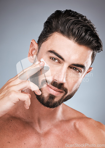 Image of Skincare, face cream and portrait of man in studio isolated on a gray background for wellness. Cosmetics, dermatology and young male model apply lotion, creme or moisturizer product for facial health