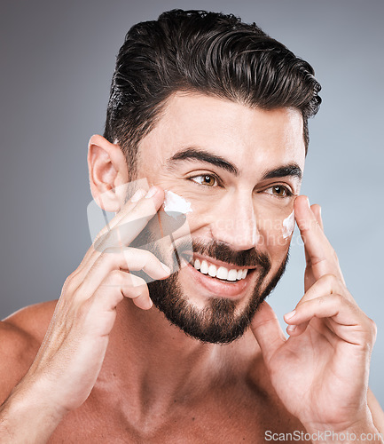 Image of Skincare, cream and face of man in studio isolated on a gray background for wellness. Thinking, dermatology and happy male model apply lotion cosmetics, creme or moisturizer product for facial health