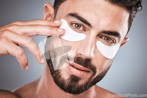 Image of Face, skincare and man with eye patches in studio isolated on a gray background for wellness. Portrait, dermatology and male model with cosmetics, facial treatment or mask product for healthy skin.