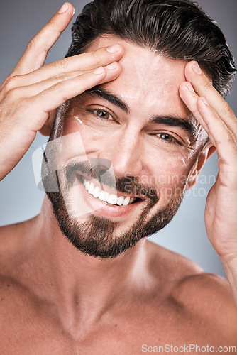 Image of Face, skincare and man with cream in studio isolated on a gray background for facial wellness. Portrait, forehead cosmetics and happy male model apply lotion, healthy creme or moisturizer product.