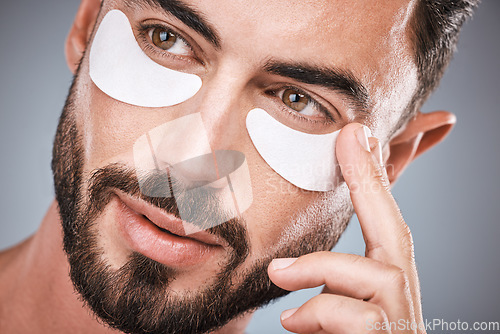 Image of Face, man and skincare eye patches in studio isolated on a gray background for wellness. Thinking, beauty dermatology and male model apply eyes mask, cosmetics or facial treatment for healthy skin.