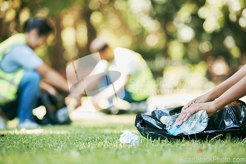 Image of Volunteer hands, plastic and pollution while cleaning park for community service for environment and recycling. People group helping with bottle and trash bag outdoor on grass for ngo clean project